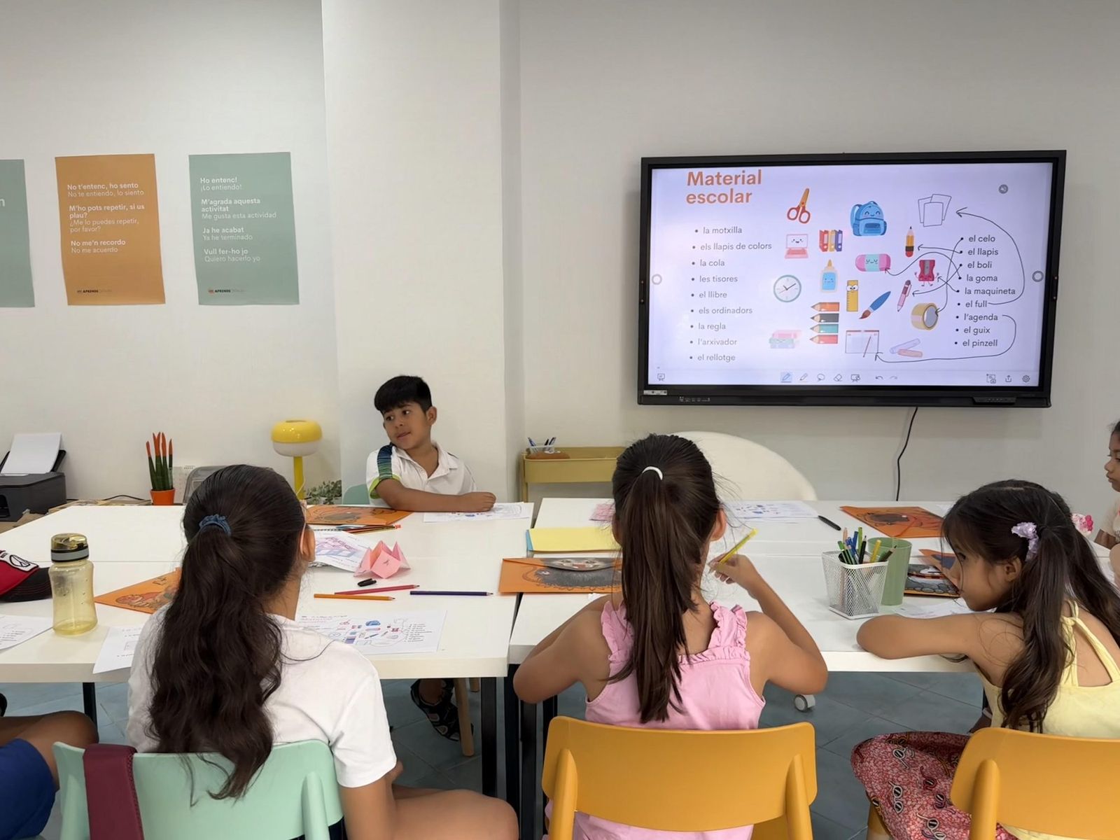 Niños aprendiendo vocabulario de material escolar en el aula de Aprendecatalan